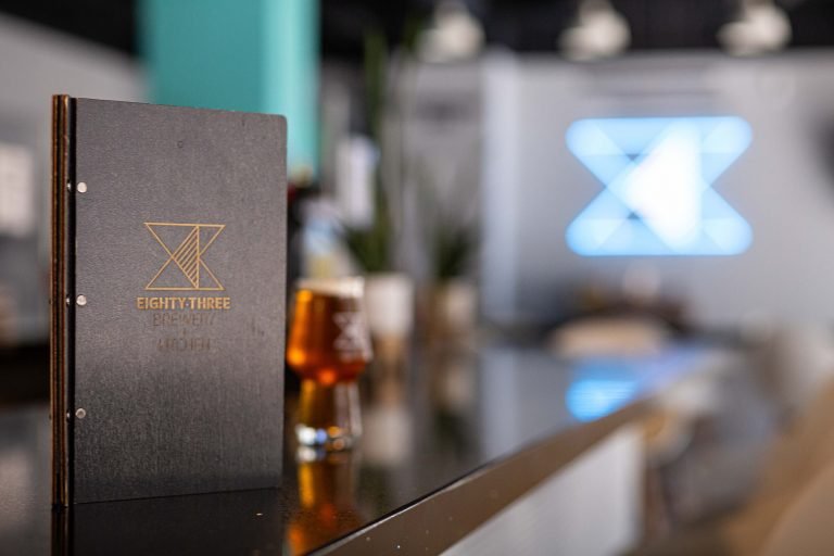 Bar top with menu and beer featuring neon sign
